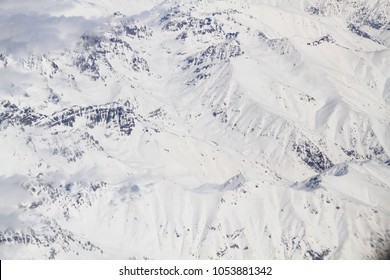 The almost abstract view of snowy peaks of the Caucasus Mountains in Georgia, Europe, on sunny day. Aerial view. Mighty tops of the mountains are completely covered with fresh snow. Winter background.