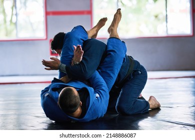 Almost All Fights End Up On The Ground. Full Length Shot Of Two Young Male Athletes Sparring On The Floor Of Their Dojo.