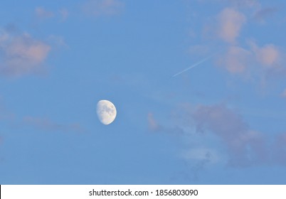 almost complete moon in the partly cloudy sky and the wake of an airplane - Powered by Shutterstock