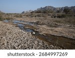 Almost dry river bed and distant rocky mountains in Hatta
