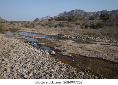 Almost dry river bed and distant rocky mountains in Hatta
