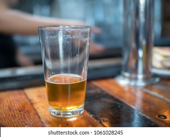 Almost Empty Pint Glass Of Beer Sitting On Wooden Bar For Last Call