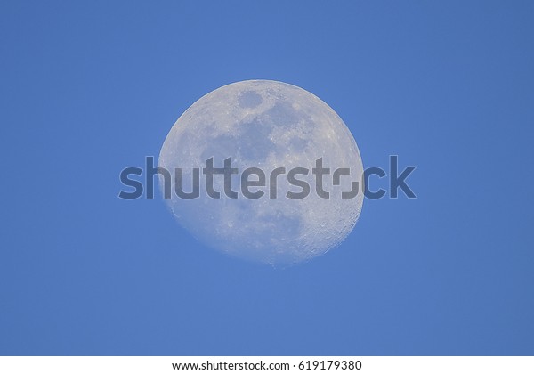 Almost full\
moon at daylight with clear blue\
sky