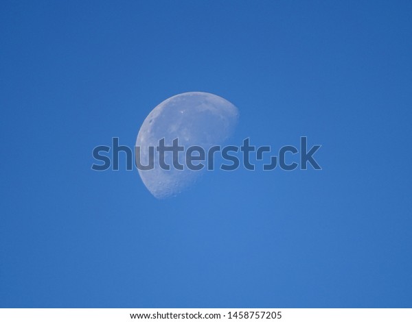 Almost\
full moon in the sky in the afternoon. Blue\
sky