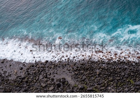 Almost graphic impression of the view of a black pebble beach from above. Blue sea, white waves and black beach, La Palma, Canary Islands