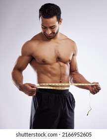 Almost at my ideal weight. Shot of a man measuring his waist using a measuring tape against a studio background.