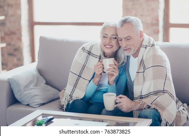 It Is Almost Winter, So Cold Outside, But So Sweet Time We Spend Together! Happy Cheerful Peaceful Couple Of Pensioners Are Resting,  Relaxing, Hugging, Drinking Tea With Closed Eyes At The Weekend