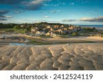 Alnmouth Village, Northumberland, Uk. Photo taken just after sunrise with the rippled sand catching the light. A few small boats can be seen waiting for the tide to come in.