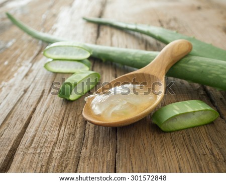 aloe vera gel on wooden spoon with aloe vera on wooden table