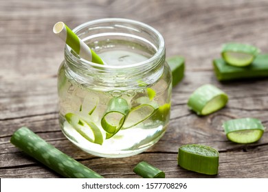 Aloe Vera green cocktail for healthy body and body. Aloe pulp slices in a glass jar and leaves on a wooden table.
