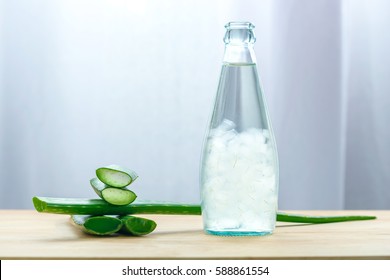 Aloe vera juice in bottle with fresh aloe vera leaves on wooden background