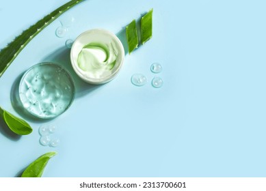 Aloe vera plant leaves and cosmetic gel for skin care  on blue background, top view, copy space. Natural organic aloe vera cosmetic gel in petri dish.