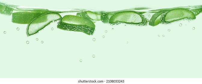 Aloe vera slices under water on green background. Copy space, banner. - Shutterstock ID 2108033243