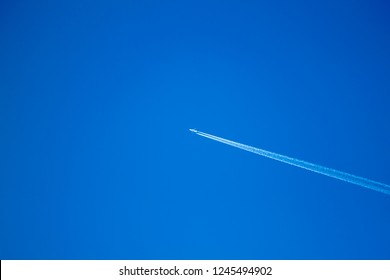 alone airplane flying in clear blue sky with white condensation trails