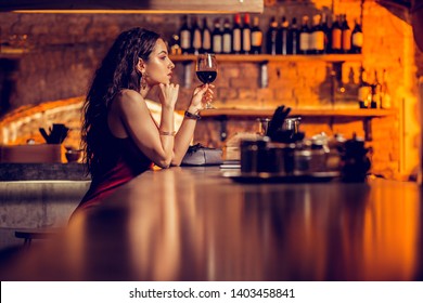 Alone In Bar. Long-haired Beautiful Woman Wearing Bracelets Drinking Wine Alone In The Bar