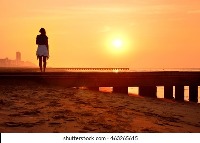 Alone beautiful young woman looking at summer sunrise on empty morning beach. Original wallpaper for theme thinking and with space for your montage