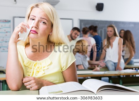 Alone european student being bullied by a group of students her chin on her hand