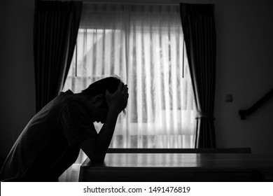 Alone Man Silhouette Sitting On The Table Closed With Curtains In Home, Depression And Anxiety Disorder Concept.