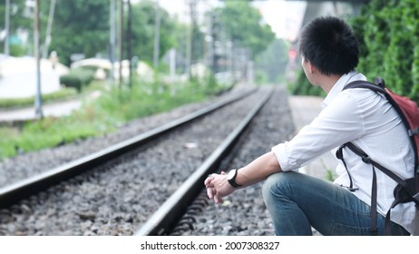 Alone Man Sit On Along A Railway Track To Meet A Train. Vacation Concept.