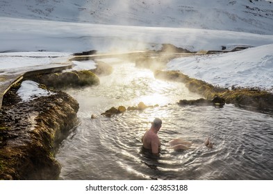 Alone man sitting in hot thermal river in Iceland sourrounded by winter snowy landscape - Powered by Shutterstock