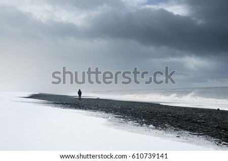 Alone man standing on the dark nordic beach in Iceland - thinking, loneliness concept photo
