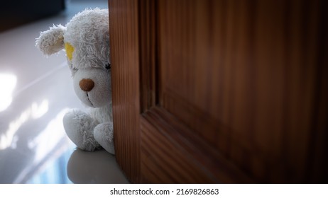 Alone teddy bear sitting beside door. cute toy doll in room with free  space. card or poster for lonely, sad, broken heart or international missing children's day concept.