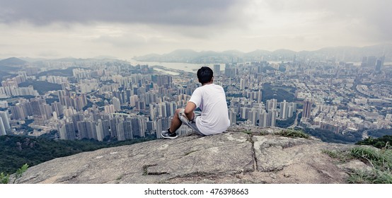 Alone Tourist Man Sit On Rock , Hong Kong City In Background , Feel Lonely 