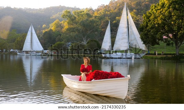 Alone women\
celebrating International Women\'s Day and smiling sailing on wooden\
board on sunset. Independent single romantic woman arranges her own\
date at the nature summer lake\
