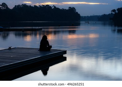 Alone Women Relax On Wooden Dock At Peaceful Lake, Silhouette