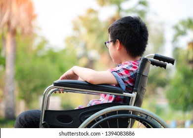 Alone Young Disabled Man On Wheelchair In The Park, Patient Is Relaxing In Garden Decorations Of The Hospital Feeling Of Missing Someone, Lonely