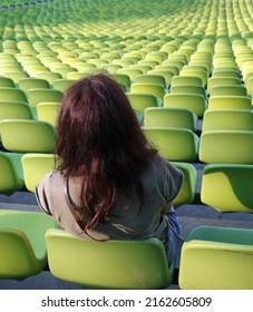 Alone Young Woman On The Seat In The Bleache Of Stadium And Many Free Seats