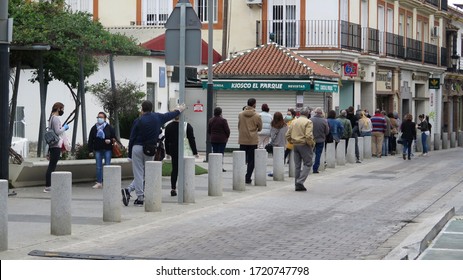 Alora, Spain - Apill 4, 2020: Large Crowd Outside Bank On Pension Day Respecting Social Distancing Rules In Andalusian Village