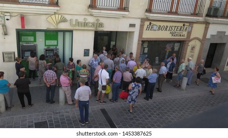 Alora, Spain - June 28, 2019: Large Crowd Outside Bank On Pension Day In Andalusian Village