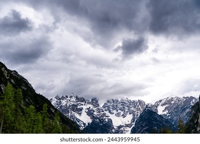 Alpen, South Tyrol - Italy - 06-07-2021: Close-up of dark clouds looming over partly snow-covered mountain peaks in the Alps, creating a dramatic scene - Powered by Shutterstock