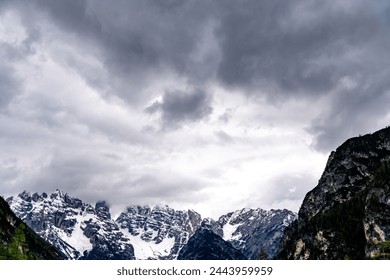 Alpen, South Tyrol - Italy - 06-07-2021: Close-up of dark clouds looming over partly snow-covered mountain peaks in the Alps, creating a dramatic scene - Powered by Shutterstock