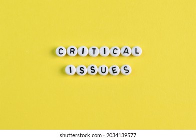 Alphabet Beads With Text CRITICAL ISSUES Isolated On A Yellow Background