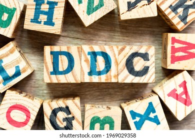 Alphabet letter block in word DDC (Abbreviation of Division of disease control, Direct digital control, Display Data Channel or Dewey Decimal Classification) with another on wood background