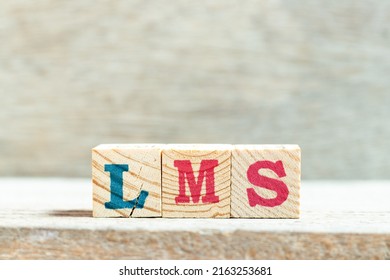 Alphabet letter block in word LMS (Abbreviation of Learning management system) on wood background