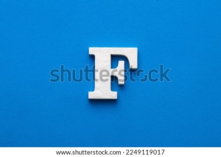 Alphabet letter F - White wooden letter on blue foamy background