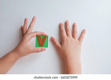 Alphabet. Letter V. Hands of the child hold letters. Learn ABC alphabet with baby.