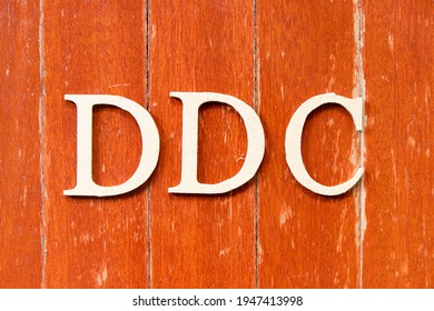 Alphabet letter in word DDC (Abbreviation of Division of disease control, Direct digital control, Display Data Channel or Dewey Decimal Classification) on old red color wood plate background