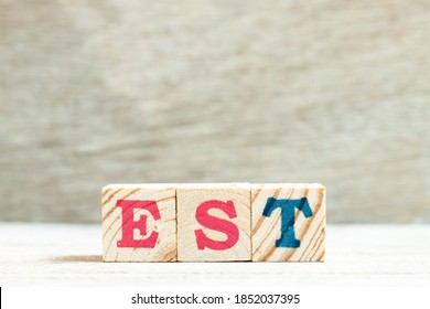 Alphabet Letter In Word EST (abbreviation Of Established, Estimated, Eastern Time Zone, Expressed Sequence Tag) On Wood Background