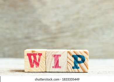 Alphabet letter in word WIP (Abbreviation of work in progress) on wood background