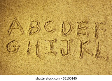 alphabet letters  handwritten in sand on beach