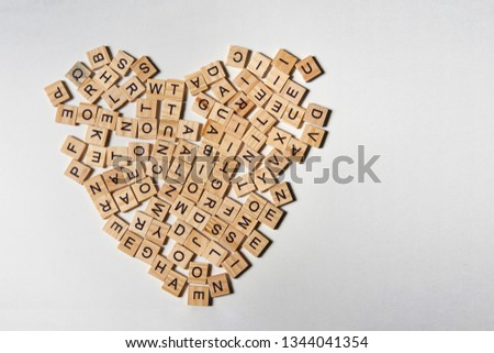 Alphabet letters on wooden square pieces forming heart shape on white background