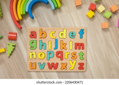 Alphabet Wooden Board With Colored Font Letters In Cells Closeup Isolated On White. Boy Girl Kid Arms Intellect Game Playing Early Development Primary Education Letters Learning