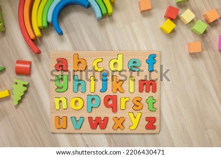 Alphabet wooden board with colored font letters in cells closeup isolated on white. Boy girl kid arms intellect game playing early development primary education letters learning