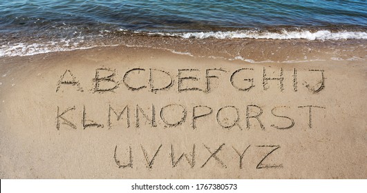 alphabeth handwritten in the sand on the beach at the sea to make your own text