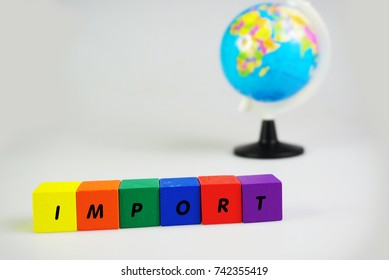 Alphabetical cubes containing Import and Export words. Selective focus on the cube and out of focused of world globe. Isolated on white background.
