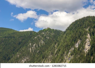 Alpine Chalet on the crest of a wooded hill, against a blue sky with clouds. - Shutterstock ID 1283382715